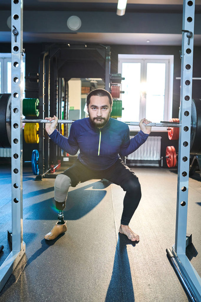 Πορτρέτο του νεαρού αθλητή με τεχνητό πόδι εργάζονται έξω με μπάρα στο γυμναστήριο - Φωτογραφία, εικόνα