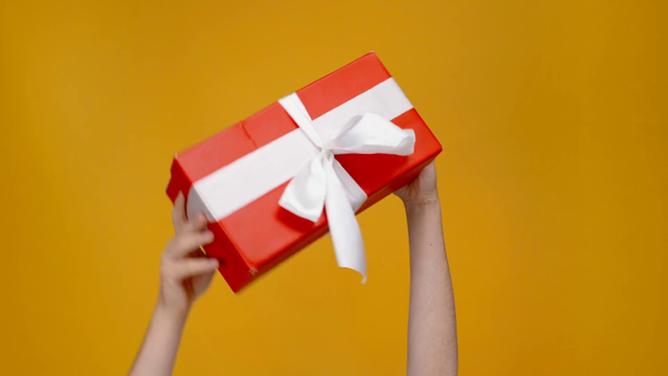 обрезанный вид человека, представляющего красную подарочную коробку с лентой изолированы на желтый
 - Кадры, видео
