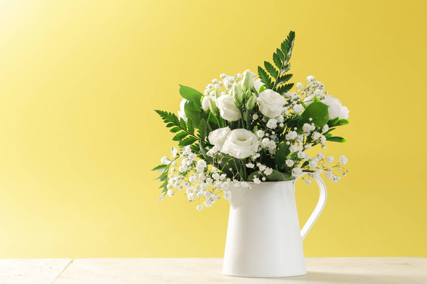 大理石のテーブルとテキストのためのスペースと黄色の背景の上に花瓶の花. - 写真・画像