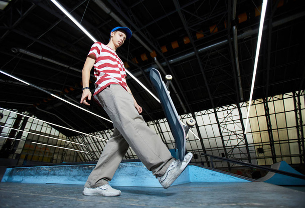 Casual skatista segurando bordo a pé e tentando mantê-lo nessa posição durante o treino no estádio
 - Foto, Imagem