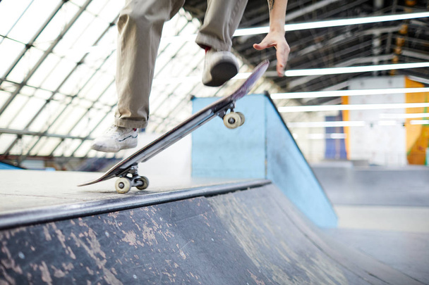 Гнучкий хлопчик-паркур стрибає в повітрі над скейтбордом і краєм спуску під час тренувань на стадіоні
 - Фото, зображення