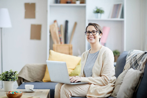 A modern nő használ laptop és látszó-on fényképezőgép-irodában, másol hely kanapén ülve portré - Fotó, kép