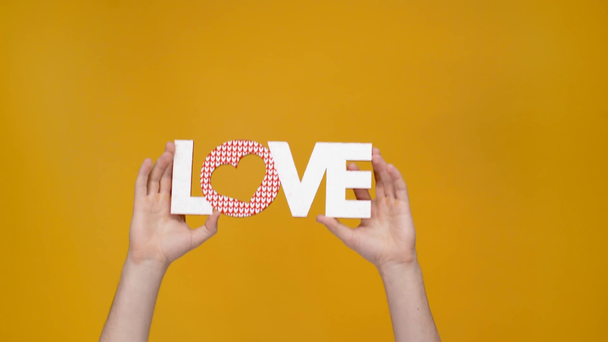 cropped view of man presenting love sign isolated on yellow - Felvétel, videó