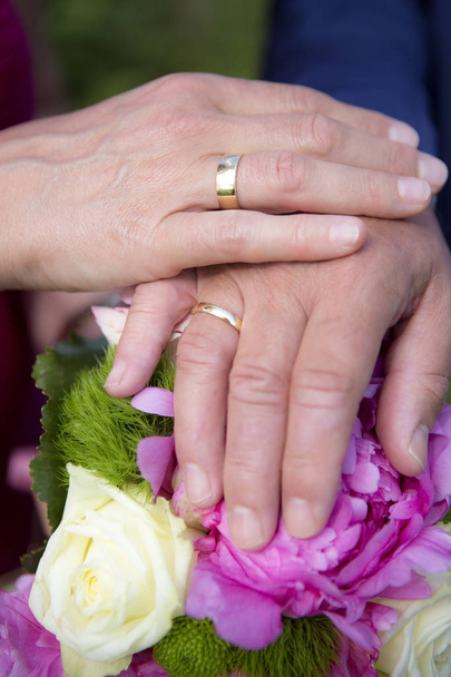 Mãos de noiva e noivo com buquê de flores
 - Foto, Imagem