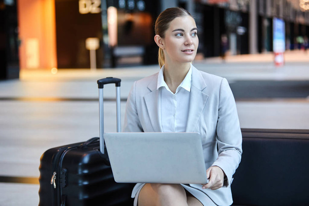 Melko nuori tyylikäs liikenainen kannettavan selailu verkossa odottaessaan lentoa lentokentällä lounge
 - Valokuva, kuva