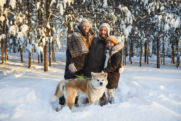 Портрет щасливої сім'ї, насолоджуючись прогулянкою з собакою в прекрасному зимовому парку і дивлячись на камеру, копіювати простір
 - Фото, зображення