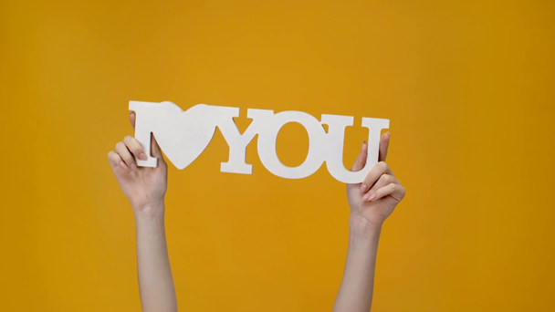 cropped view of woman presenting 'i love you' sign isolated on yellow - Footage, Video