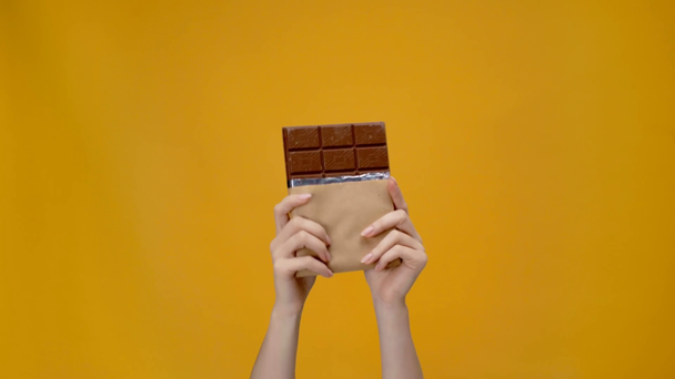 cropped view of woman presenting chocolate isolated on yellow - Footage, Video