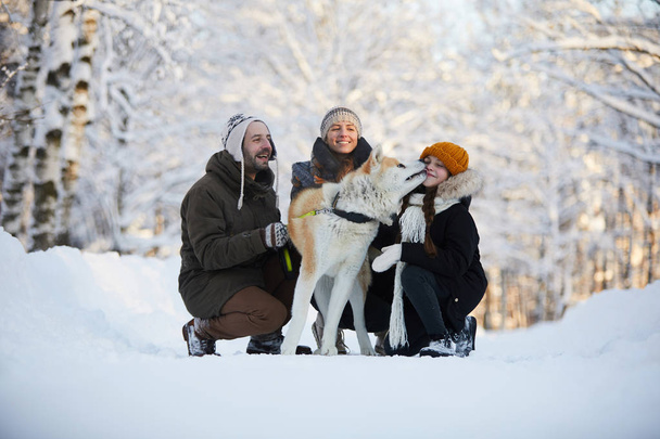 Portrét šťastné rodiny, která si užívá procházky se psem v krásném zimním parku, místo kopírování - Fotografie, Obrázek