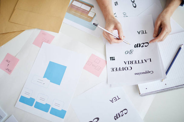 Immagine di sfondo di mani femminili che tengono le stampe per il disegno tipografico sparse sul tavolo in officina, spazio copia
 - Foto, immagini