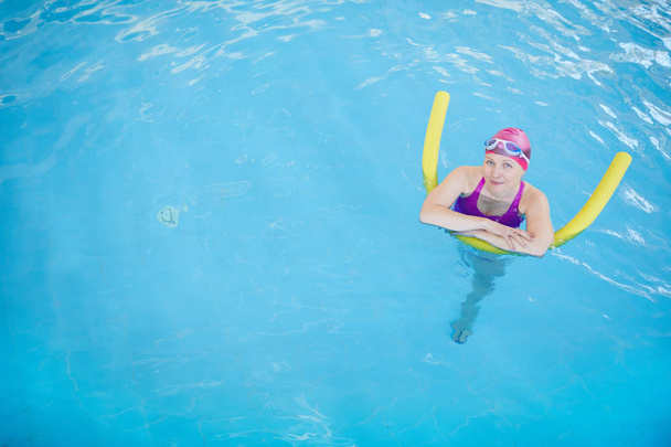 Havuzda yüzme ve kamera bakarak mutlu yaşlı kadın üst görünüm portre, kopya alanı - Fotoğraf, Görsel
