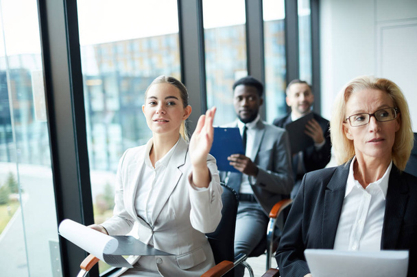 Un délégué confiant levant la main pour poser ou répondre à une question lors d'un séminaire d'affaires ou d'un forum politique
 - Photo, image