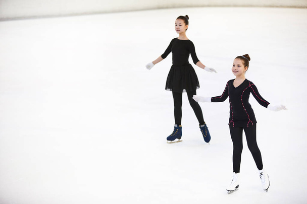 High angle portrait of two happy girls figure skating on ice rink posing gracefully, copy space - Photo, Image