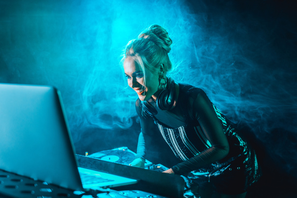 Dumanlı gece kulübünde DJ ekipmanları kullanan güzel mutlu dj kız  - Fotoğraf, Görsel
