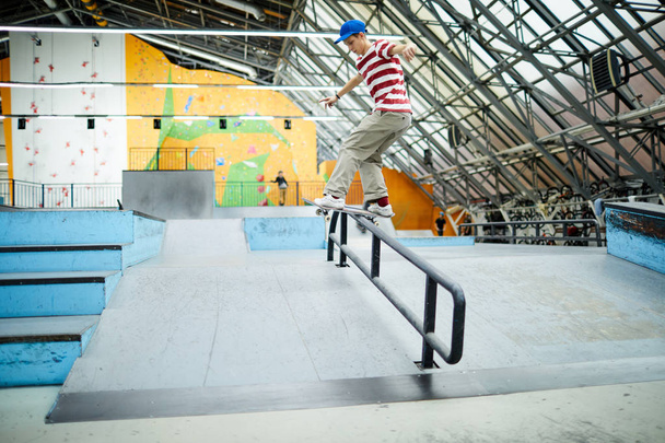 Agile jeugdige skateboarder oefenen beweging op hek pijp tijdens de training op speciale gebied - Foto, afbeelding