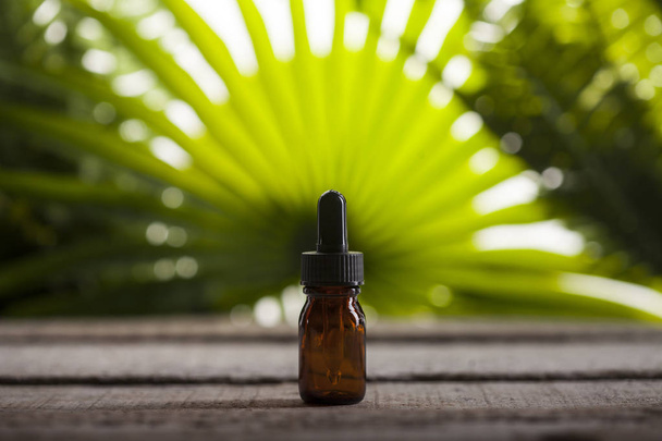 Kosmetikflasche für ätherisches Öl auf grünem Hintergrund - Foto, Bild