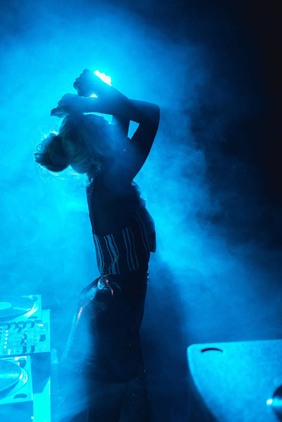 silhouette of dj woman standing in nightclub with smoke   - Photo, Image