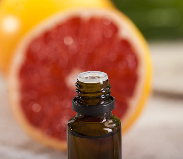 Grapefruit Essential Oil on green leaves background - Photo, image