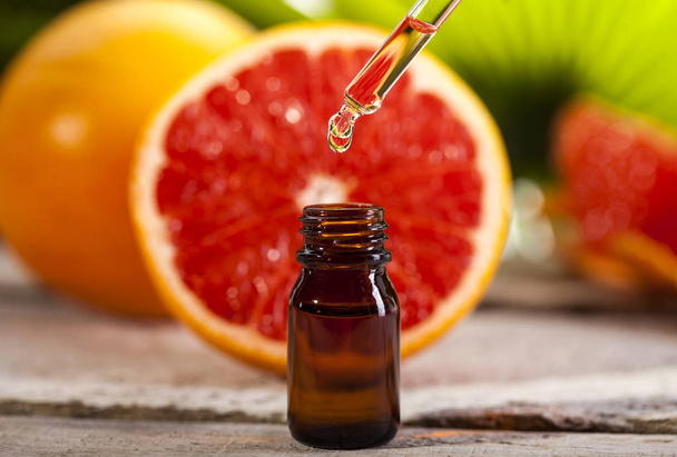 Grapefruit Essential Oil on green leaves background - Foto, afbeelding