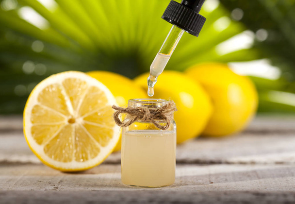 Lemon Essential Oil on green leaves background - Foto, imagen