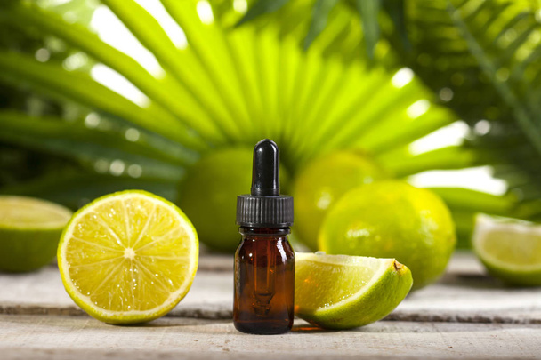 Lime Essential Oil on green leaves background - Foto, afbeelding