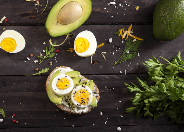 Bruschetta with avocado, cheese, egg, sesame on wooden table - Foto, afbeelding