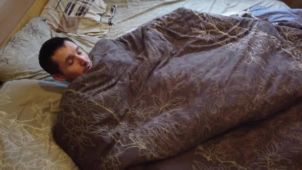 Mann schläft und wacht allein im Bett auf, mit Nahaufnahme des Gesichts. Kopfschuss eines erwachsenen kaukasischen Mannes in seinen 30er Jahren mit Kopf auf Kopfkissen am Morgen. - Filmmaterial, Video