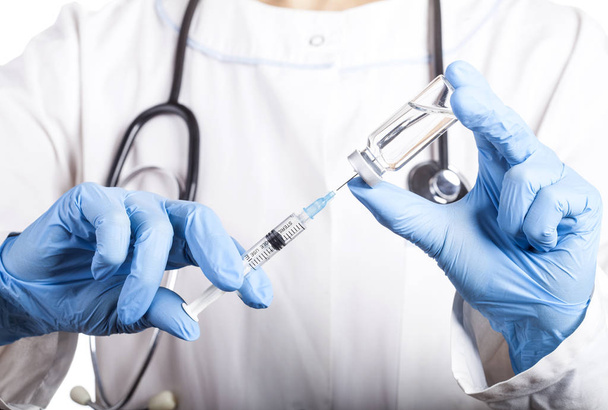 Doctor holding a syringe and a bottle with an injection solution - Foto, afbeelding