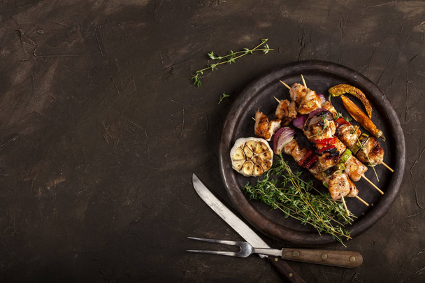 Grilled chicken skewers with spices and vegetables in a pan on dark background - Φωτογραφία, εικόνα