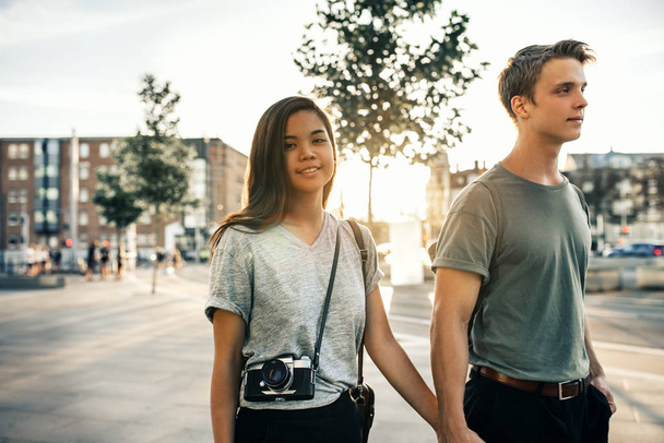 Portrait of a smiling young woman exploring the city streets with her boyfriend in the late afternoon - Fotografie, Obrázek