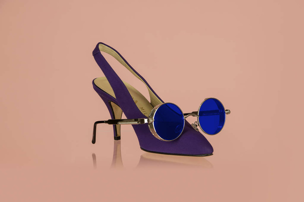 Фіолетові жіночі черевики з блакитними окулярами на рожевому фоні
 - Фото, зображення