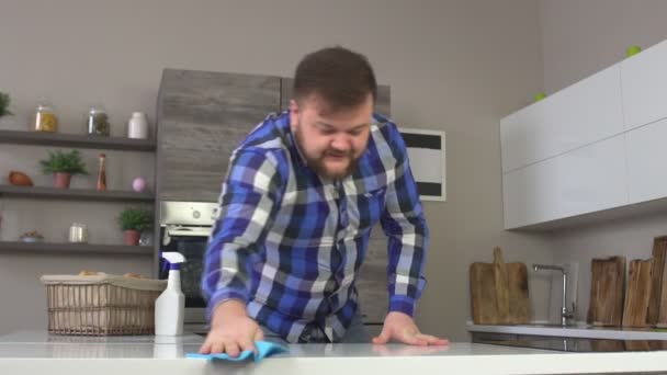 A caucasian man rubs dust in a modern kitchen, slow motion, housecleaning - Video