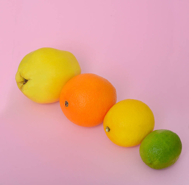 Quince orange lime lemon on a pink background - Photo, Image