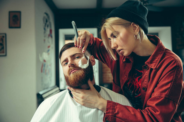 Client during beard shaving in barber shop - Fotó, kép
