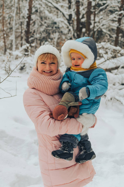 Mom walks with the child in the winter in nature. Family walks in nature in winter. Winter forest. Snow park. - Photo, Image