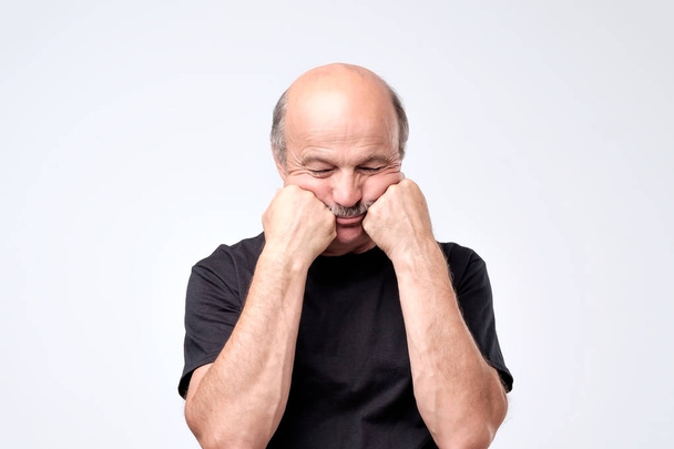 Hombre mayor con bigote cubriendo la cara con ambas manos, sintiéndose estresado ou
 - Foto, Imagen