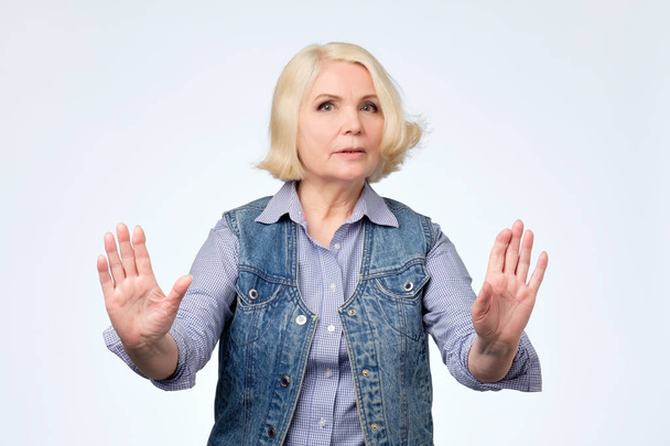 Seniorin steht mit ausgestreckter Hand und zeigt Stopp-Geste - Foto, Bild