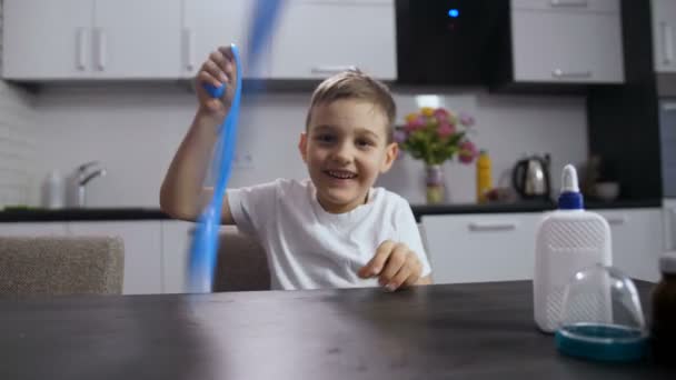 Uśmiechnięty chłopiec bawi się długo handmade szlam - Materiał filmowy, wideo
