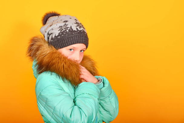 冬の服と緑色のジャケットに黄色の背景に毛皮の帽子の女の子 - 写真・画像