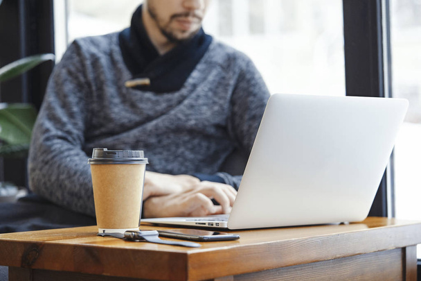 Atrakcyjny mężczyzna z laptopa i nowoczesne zegarki elektroniczne w nowoczesne Jasna kawiarnia. - Zdjęcie, obraz