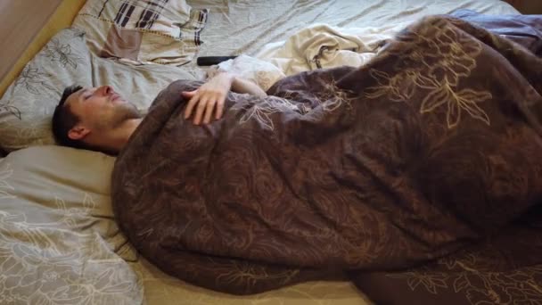 Un uomo che dorme e si sveglia da solo nel letto, da vicino. Testa di adulto caucasico di sesso maschile sulla trentina con testa sul cuscino al mattino
. - Filmati, video