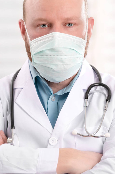 Portrait of a serious doctor wearing surgical face mask and stethoscope - Photo, Image