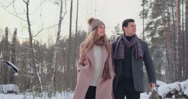 Jong getrouwd paar boswandelingen de winter. Een man en een vrouw kijken elkaar lachen en glimlachen in slow motion. - Video