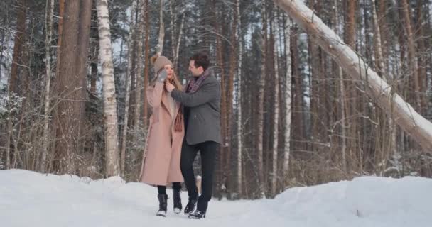 In the winter snowy forest, young men and women dressed in coats and scarves are walking and having fun. Loving couple spend together valentines day. - Footage, Video