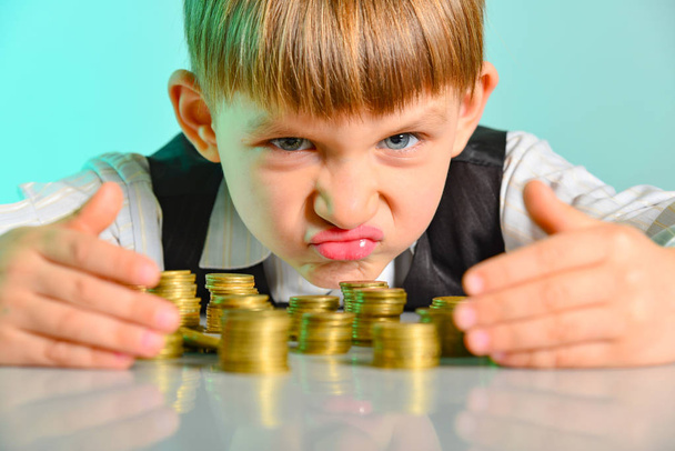 Enfant en colère et avide tient leurs pièces d'argent. Le concept de cupidité, de cupidité et de vice dès l'enfance
 - Photo, image