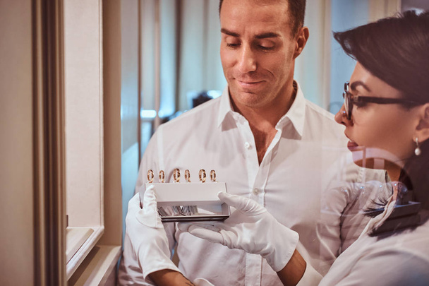 Продавец помогает клиенту выбрать обручальное кольцо в роскошном ювелирном магазине
 - Фото, изображение