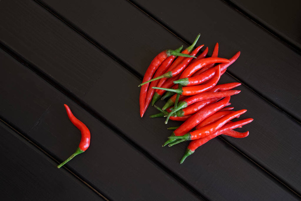 Red hot chilli pods lie on black wooden boards - Photo, Image