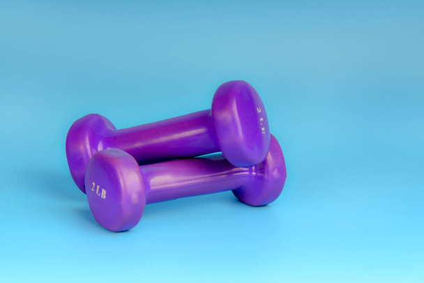 Mancuernas púrpuras para deportes sobre fondo azul
 - Foto, Imagen