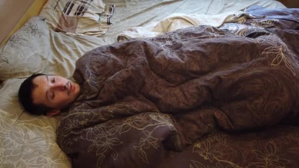 Man slapen en wakker worden alleen in het bed, close up van gezicht. Headshot van volwassen Kaukasische mannelijke persoon in zijn 30s met hoofd op het kussen in de ochtend. - Video