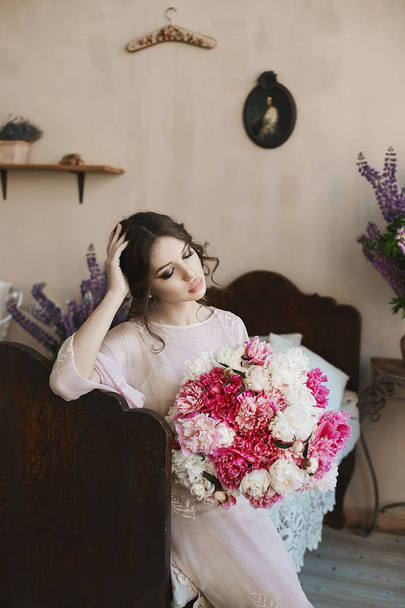 Beautiful brunette model girl with big seductive lips and with blue eyes in fashionable dress with big bouquet of pink and white flowers in her hands - Φωτογραφία, εικόνα